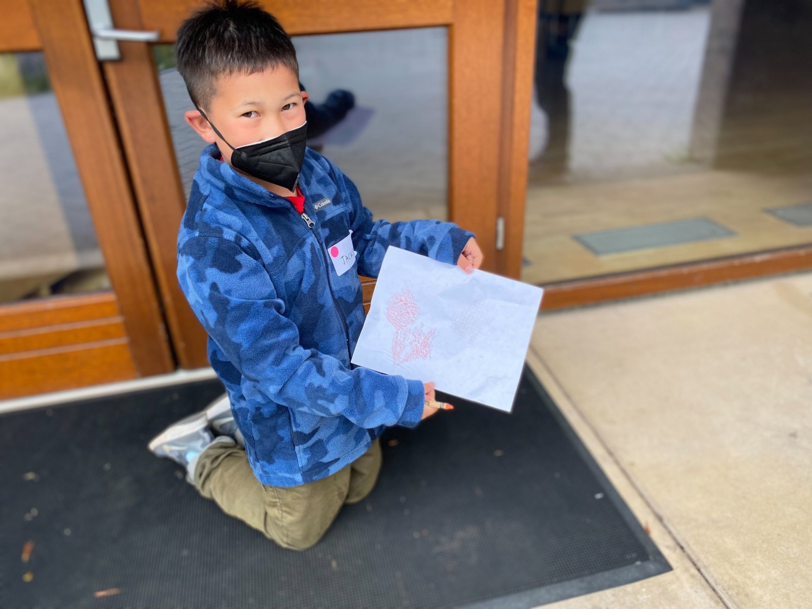 A child showing off a rubbing made from a textured surface